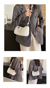 Detail of white saddle bag featuring pearl and silver heart chain with knotted strap