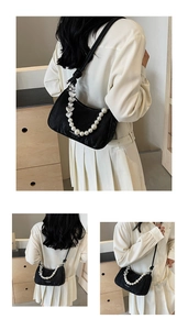 Detail of black crescent underarm bag featuring pearl beads and silver heart chain