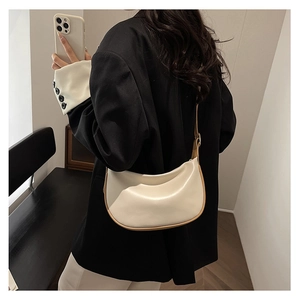 Chic cream dumpling bag with contrast piping worn over the shoulder by a model