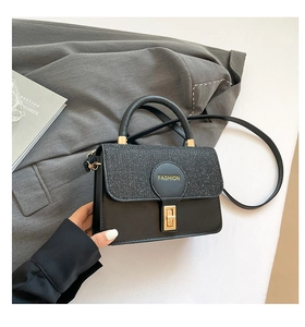 Detail of black handbag showing glitter texture, metal turn lock, and fashion logo detail