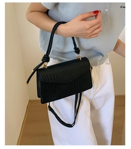 Vue détaillée du sac à main noir tressé avec poignée nouée et finitions dorées