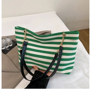 Close-up of green and white striped tote bag with black leather and gold chain straps
