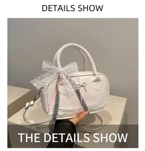 Detail showing white lace Boston bag with metallic bow and heart-shaped trim accents