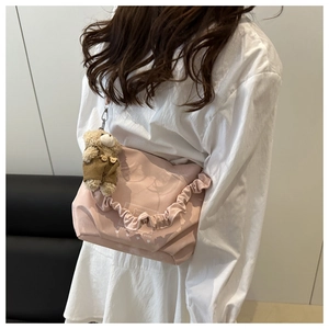 Detail of pink handbag with pleated handles, bear print and plush charm decoration