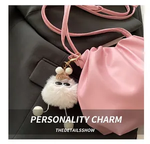 Close-up of white plush ball charm with sunglasses and hat on pink bucket bag