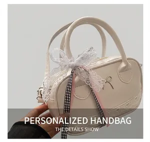Detail view of cream white lace Boston bag with oversized bow and metal buckle
