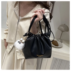 Detail view of black pleated bucket bag with gold lettering and cute plush charm
