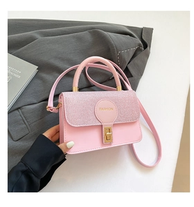 Close-up of pink square handbag with golden twist lock and shimmering flap detail