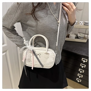 Detail der weißen Spitzen-Bostontasche mit Metalle Schleife und kariertem Band
