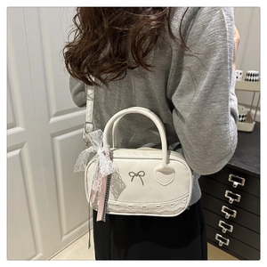 Detail of white PU leather bowling bag featuring silver bow and delicate lace trim accents