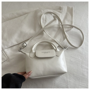 Détail d'un mini sac bandoulière en similicuir crème avec poignée et texte élégant