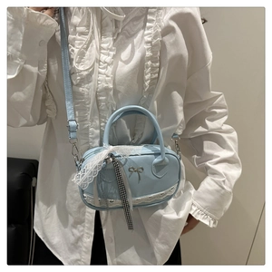 Detail of light blue crossbody bag with metal bow, lace trim and plaid ribbon accent
