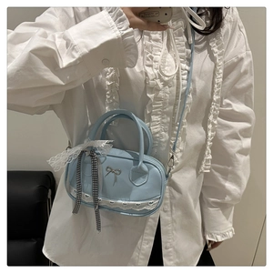 Hellblaue Mini-Handtasche mit Schleife und Spitze, am Modell in weißer Bluse gezeigt