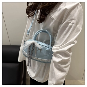 Vista laterale di una borsa a tracolla azzurra con pizzo e fiocco decorativo elegante