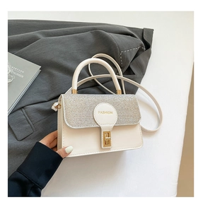 Close-up of white leather bag with silver sequined flap and golden metal twist lock