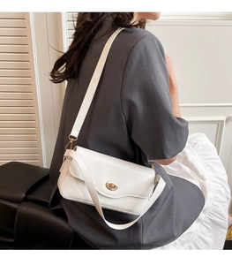 Detail of white leather shoulder bag with gold metal lock and wavy flap design