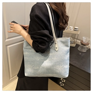 Close-up of elegant light blue tote bag featuring metallic texture and thin shoulder straps