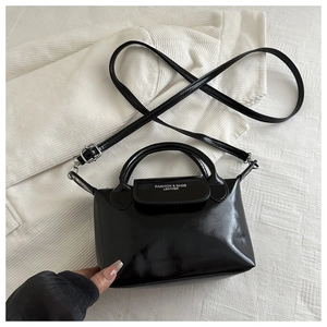 Vue à plat d'un mini sac à main en cuir noir brillant avec poignée et bandoulière réglable