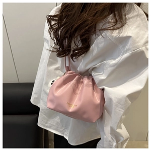 Fashionable pink dumpling bucket bag with gold lettering shown on shoulder with clean background