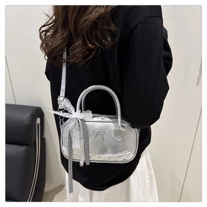 Close-up of silver crossbody bag with lace bow, ribbon detail, and heart hollow trim