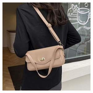 Model view showing the beige crossbody baguette bag with gold twist lock and adjustable strap