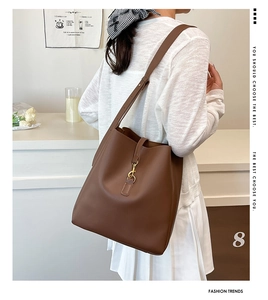 Brown leather bucket bag with gold hook clasp shown in a stylish lifestyle setting