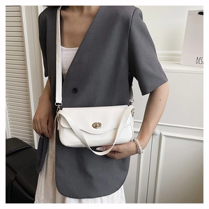 Detailed close-up of a white rectangular crossbody bag with a golden oval metal clasp