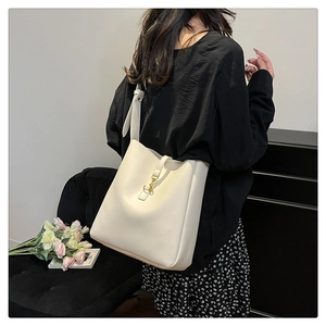 Detail of cream white leather bucket bag featuring a golden metal clasp and wide strap