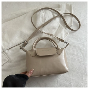 Détail d'un sac à main beige en cuir avec double poignée et logo embossé élégant