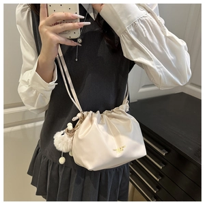 Close-up of cream pleated bucket bag with plush charm and Fashion & Bags text detail