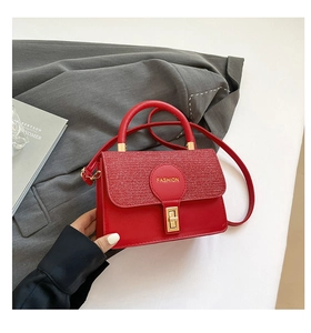 Detail of red leather crossbody bag with sequin texture and golden fashion twist lock
