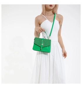 Sac bandoulière vert pailleté avec rabat et boucle métallique sur mannequin en robe