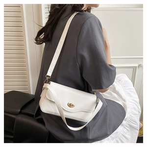 Close-up of elegant white shoulder bag featuring wavy flap and gold oval metal twist lock