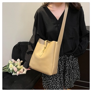 Detail of beige leather bucket bag with slim strap closure on a casual lifestyle model