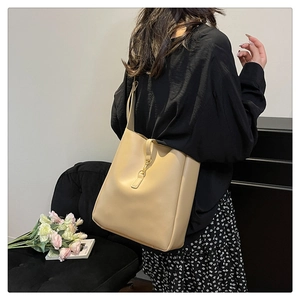 Detail view of large beige soft leather bucket bag with gold metal buckle closure