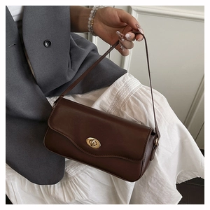 Detail of a dark brown leather handbag featuring a golden metallic twist lock closure