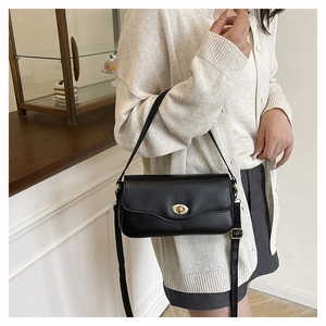 Detail of black crossbody bag with gold twist lock and adjustable long shoulder strap