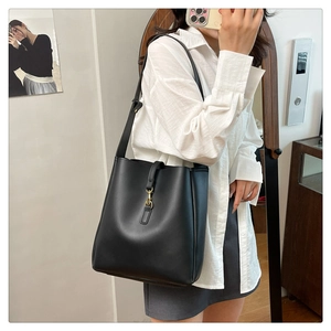 Detailed view of black matte leather bucket bag with gold hook on a shoulder strap