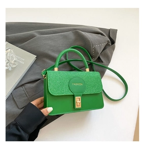 Detail of bright green PU leather handbag with sparkling flap and golden twist lock
