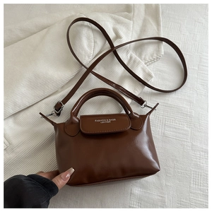 Vue de dessus d'un sac à main en similicuir marron foncé brillant avec bandoulière