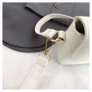 Detail of white leather shoulder bag with premium gold metal hardware on blazer background