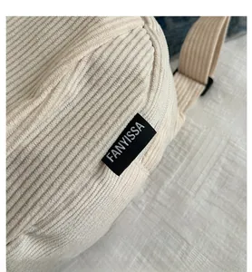 Vue macro de la texture du velours côtelé beige et de l'étiquette de la besace femme