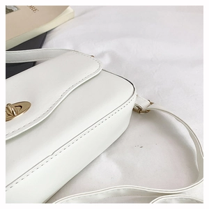 Detail of white PU leather shoulder bag with gold metal lock and neat edge stitching