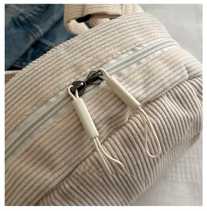 Détail des fermetures éclair doubles et de la texture velours côtelé du sac crème