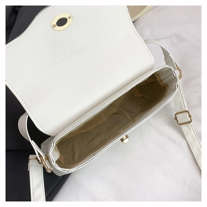 Detail view of white square bag showing khaki lining and golden twist lock closure