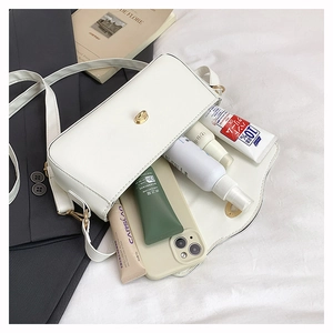 Detailed interior of a white leather bag showing storage capacity for phone and cosmetics