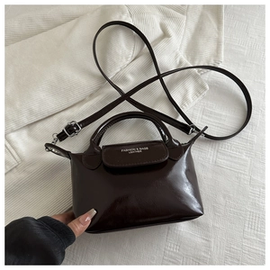 Détail d'un sac à main en cuir marron foncé brillant avec logo et bandoulière