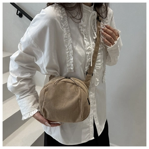 Detail of adjustable woven strap and khaki corduroy texture on the crossbody saddle bag