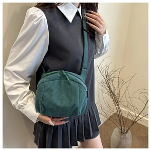 Close-up of dark green corduroy shell bag featuring fine ribbed texture and dual zippers