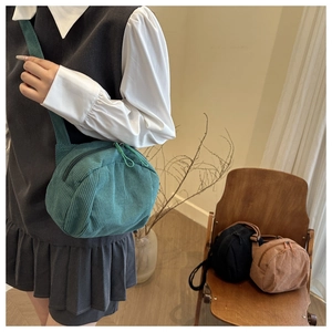 Detail of corduroy crossbody bag featuring dual zippers and vintage forest green texture